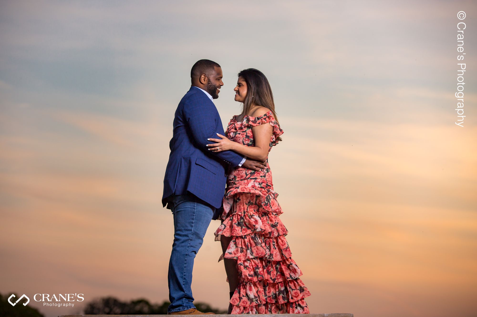 A posed image of a couple with a setting sky in the background