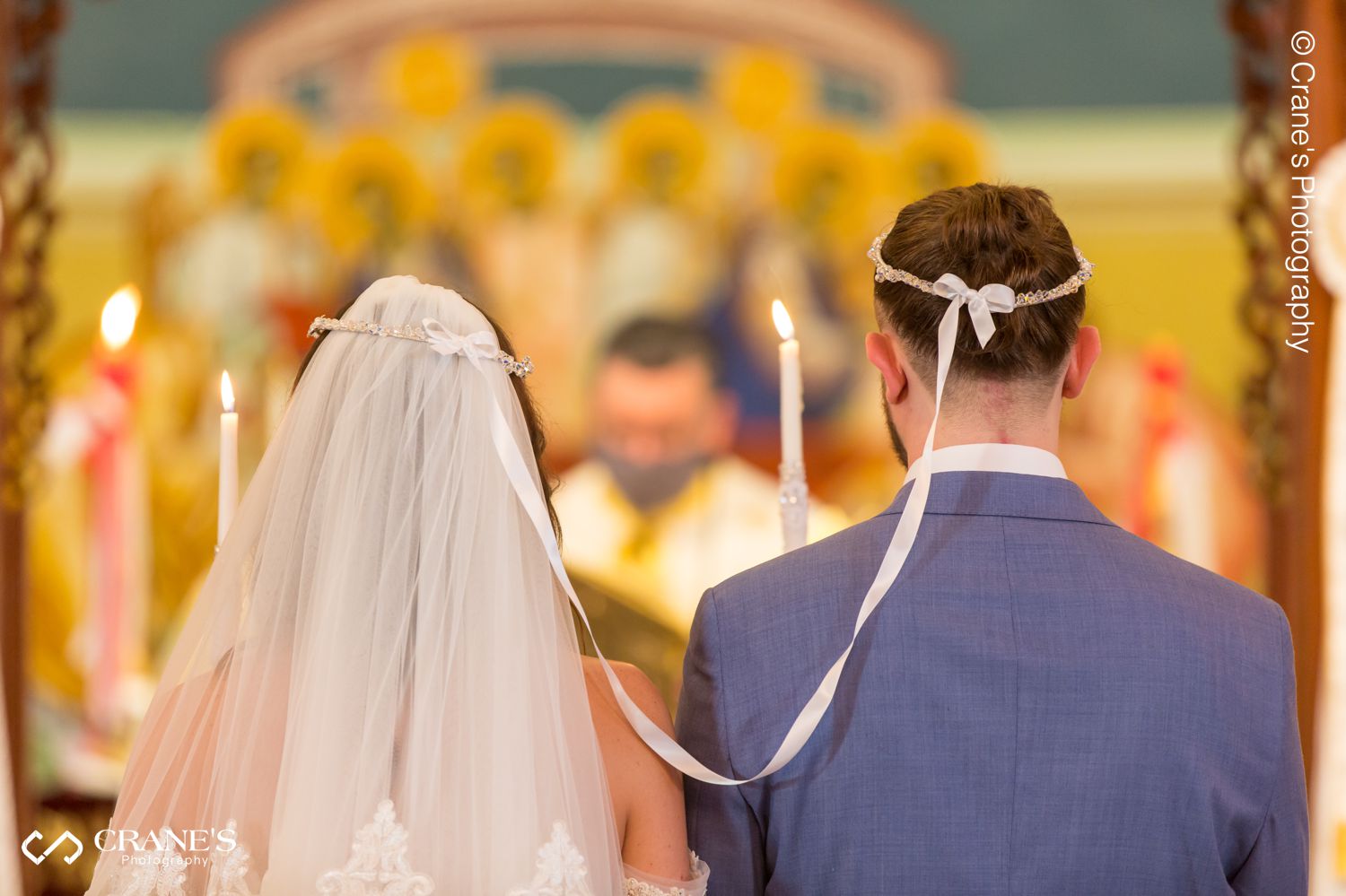 Bride and groom with their traditional greek orthodox wedding crowns at the altar of Holy Taxiarhai St. Haralambos Greek Church