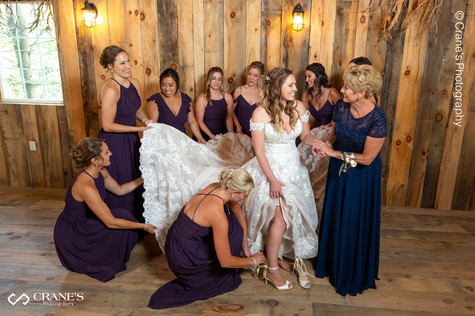 A bride is getting ready with her bridesmaids inside a barn