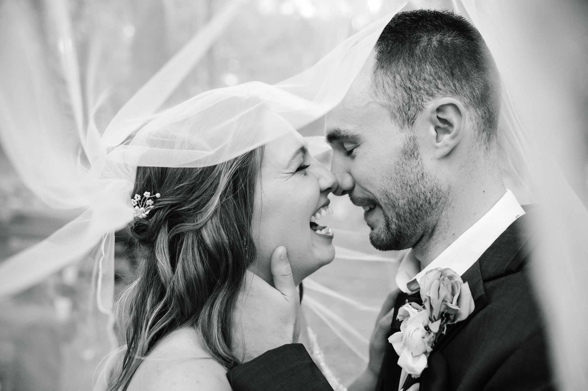 A candid image of bride and groom looking at each other under the bride's vail