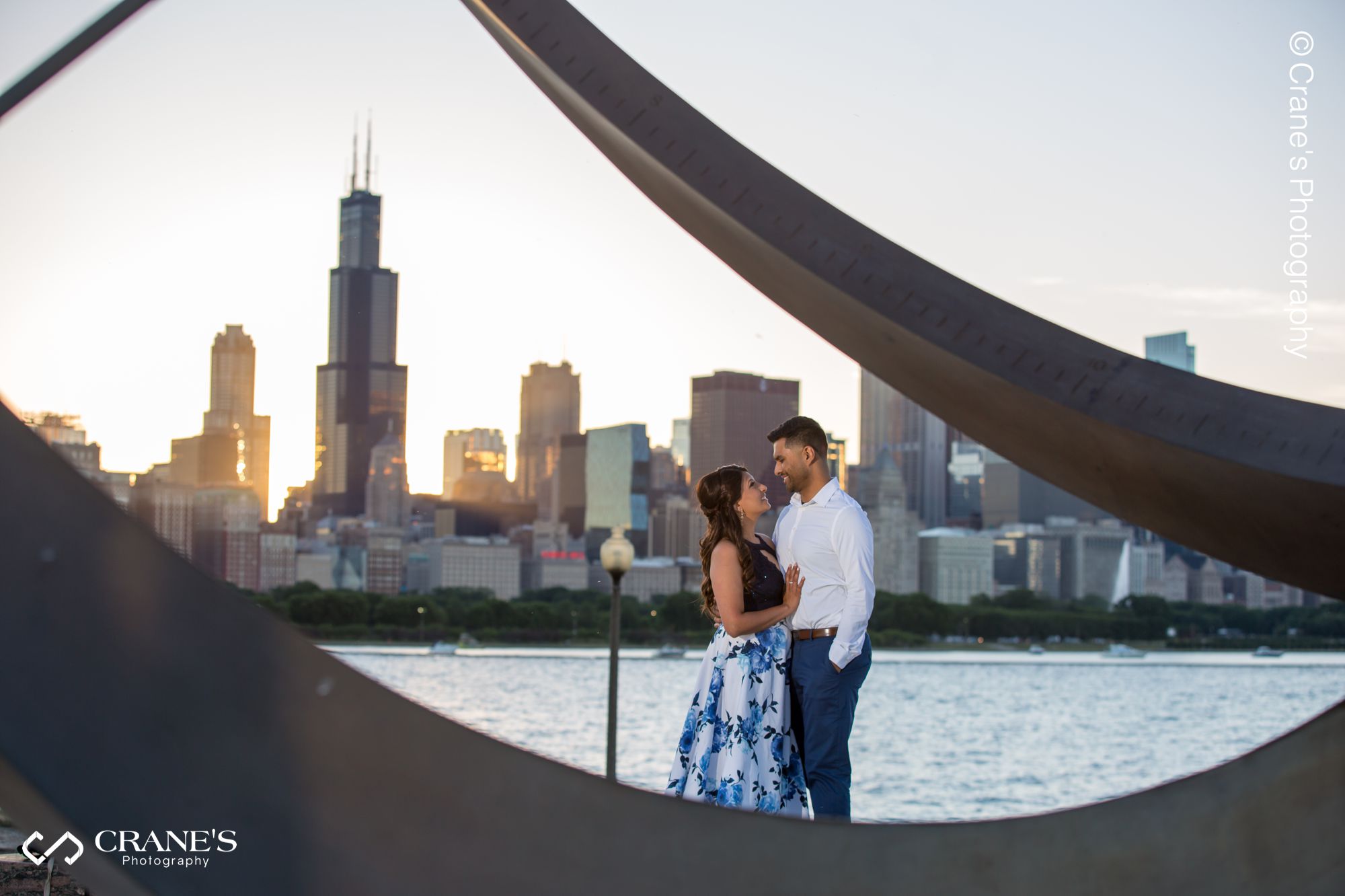 A couple posing for a photo near the Adler Planetarium with a dramatic downtown Chicago view in the background
