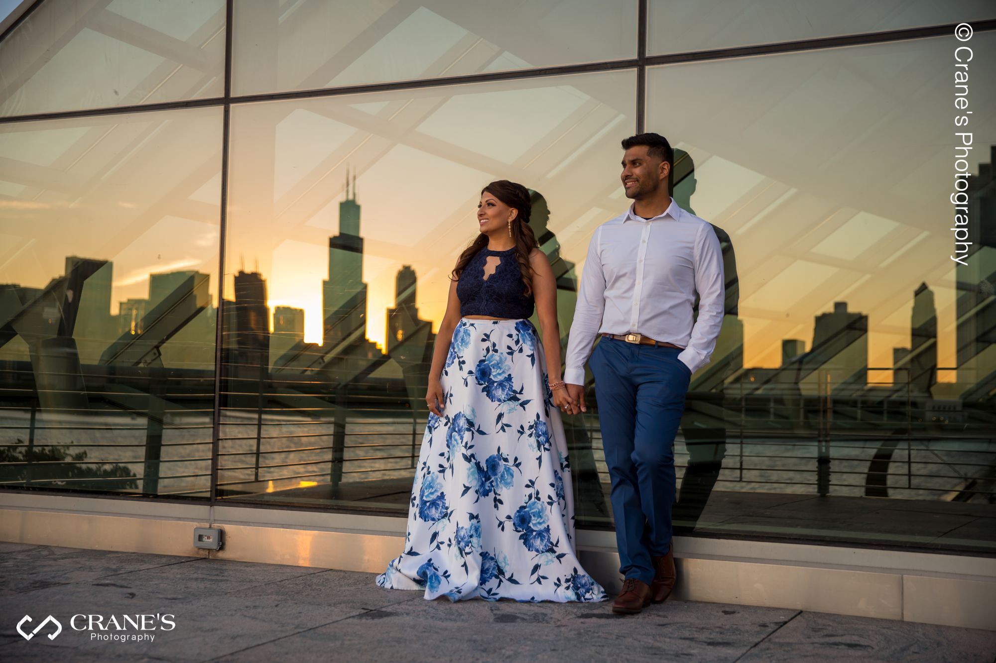 An engaged couple looking at downtown Chicago skyline at sunset over lake Michigan