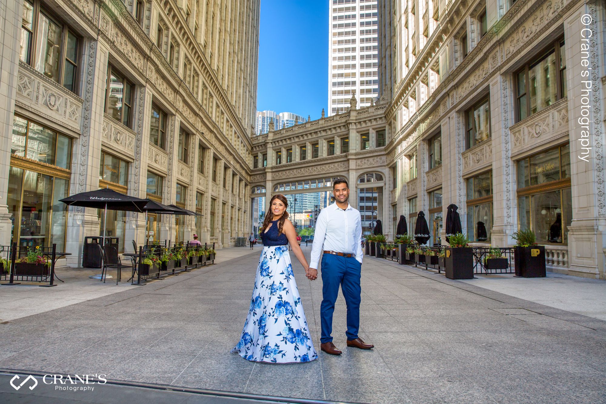 An engaged photo taken near Wrigley Building with the skywalk behind them
