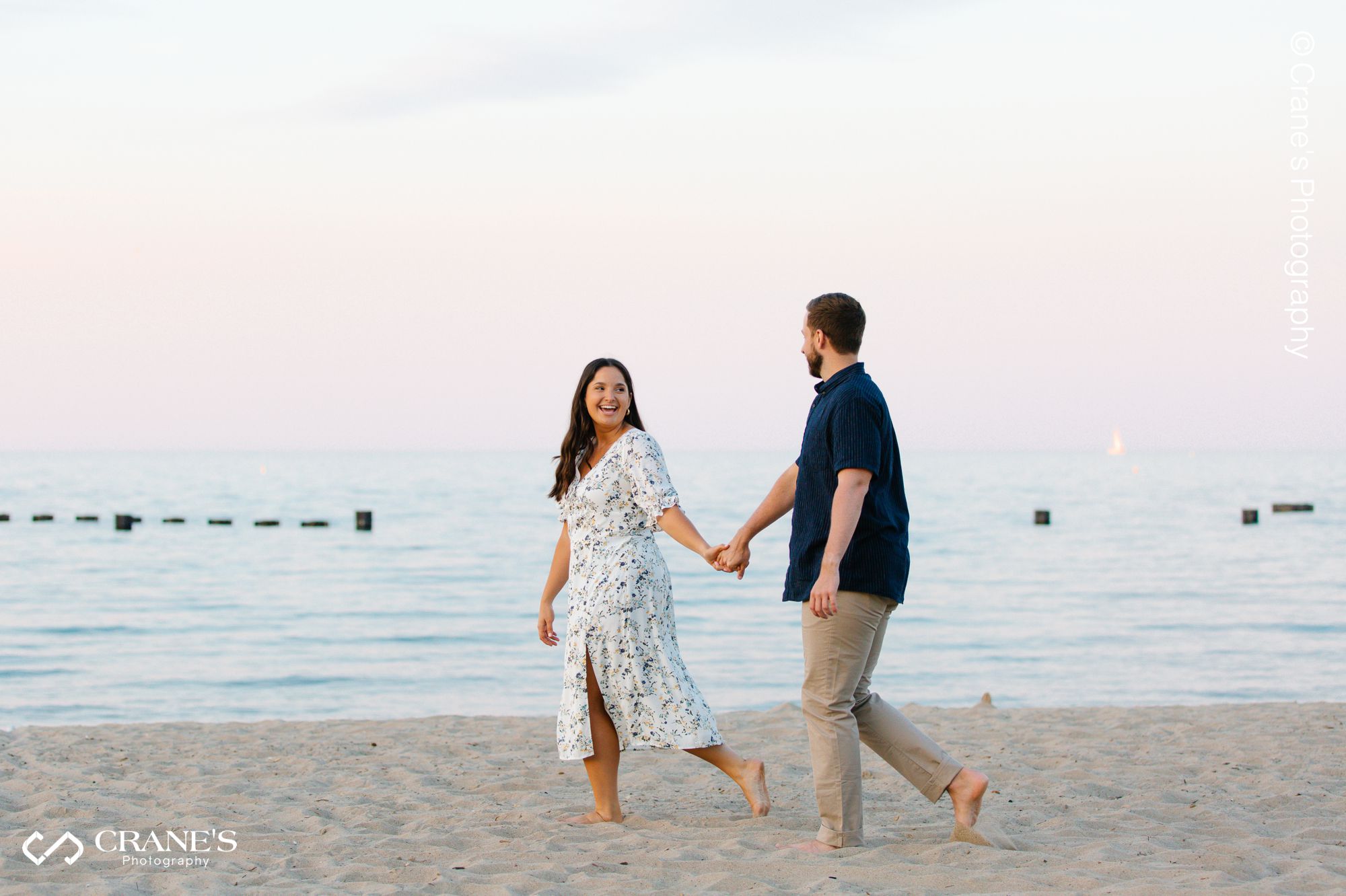 Bride and groom walk hand in hand at North Ave Beach during the golden hour for photography
