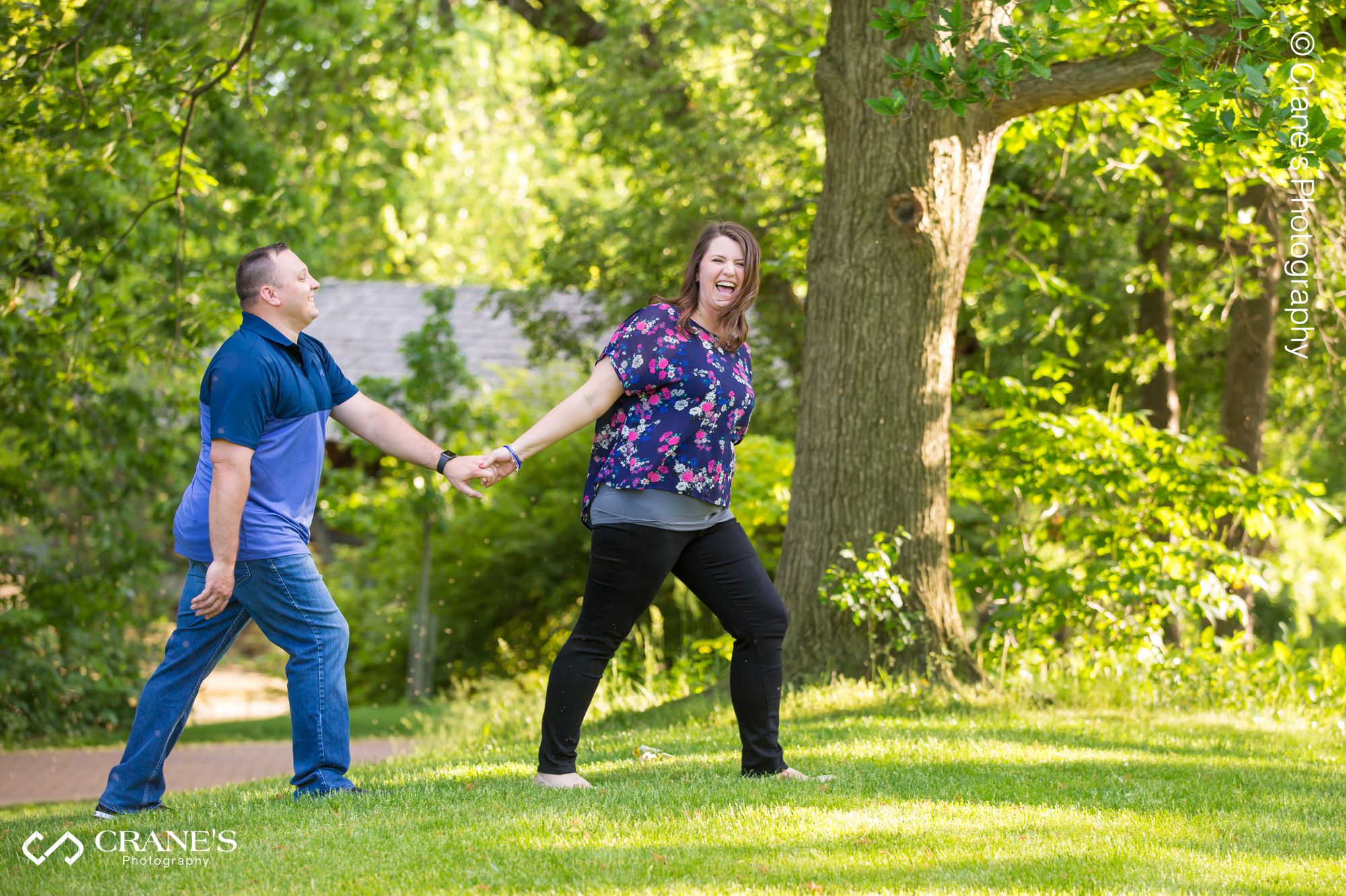 A fun moment of a couple walking during an engagement session at Naperville Riverwalk