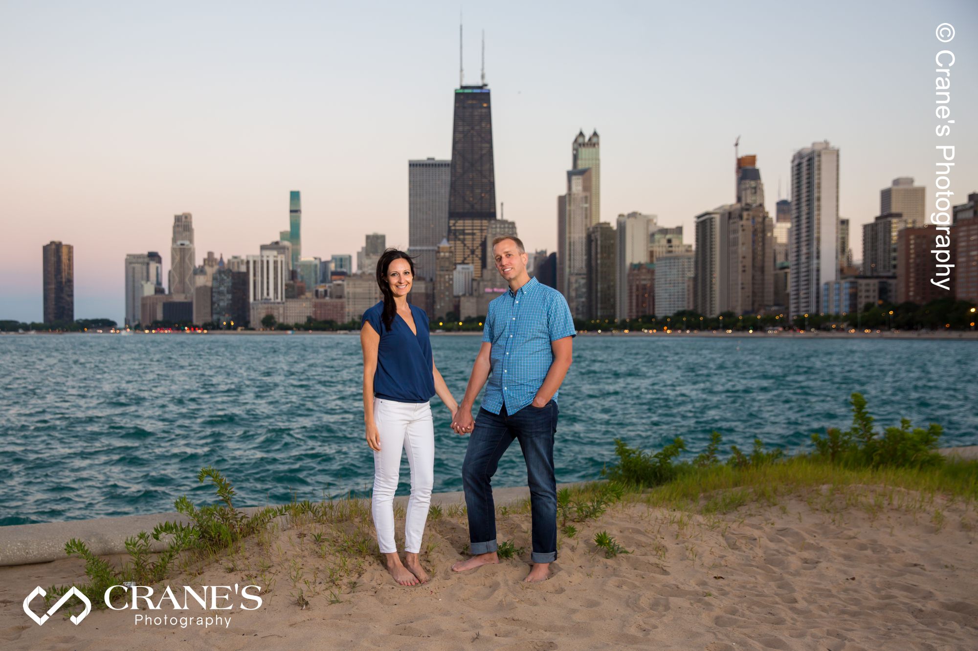 An engaged couple posed for a photo with the skyline of Chicago in the background