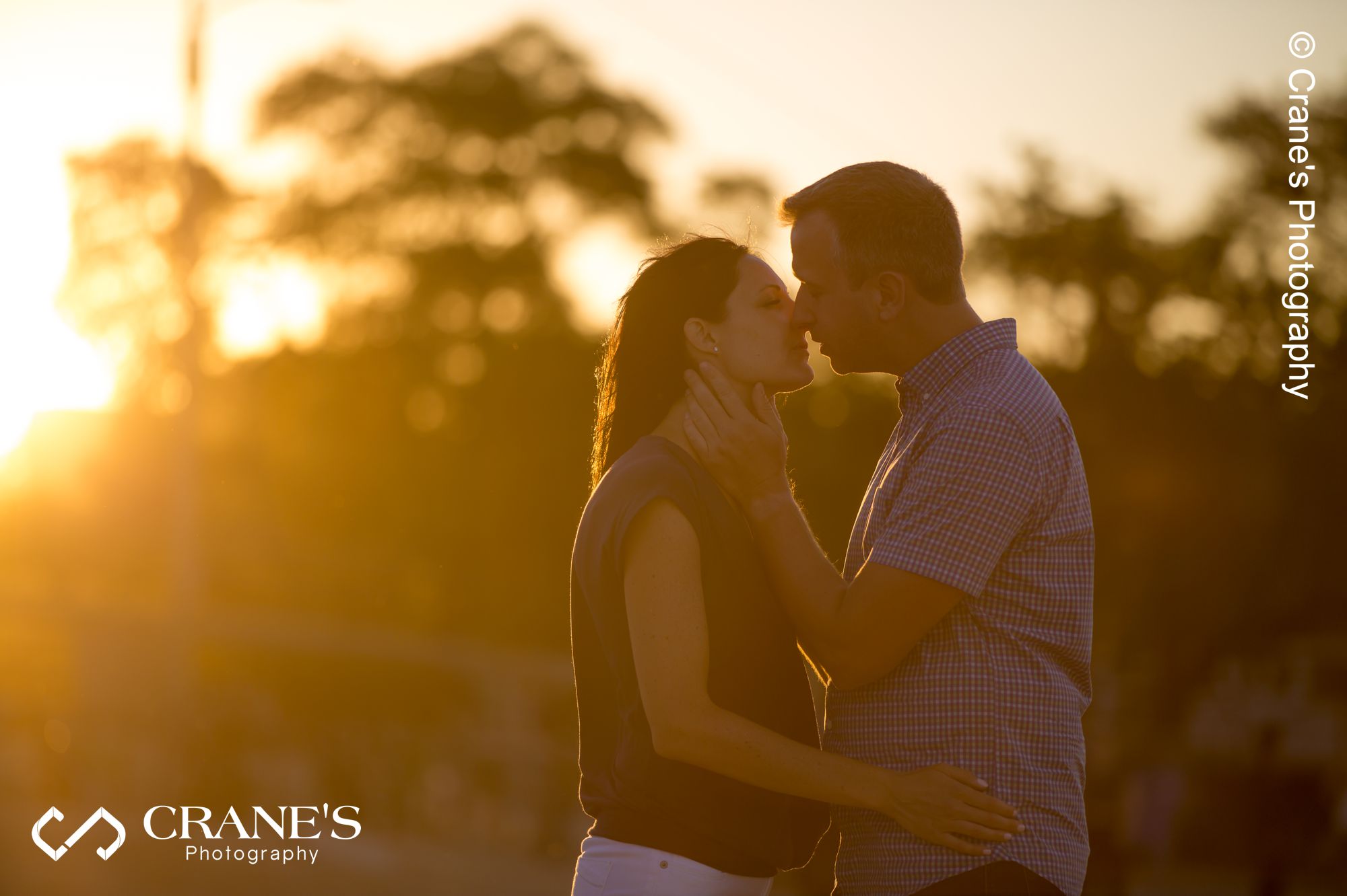 Bride and groom to-be kissing at sunset with gorgeous golden-hour light