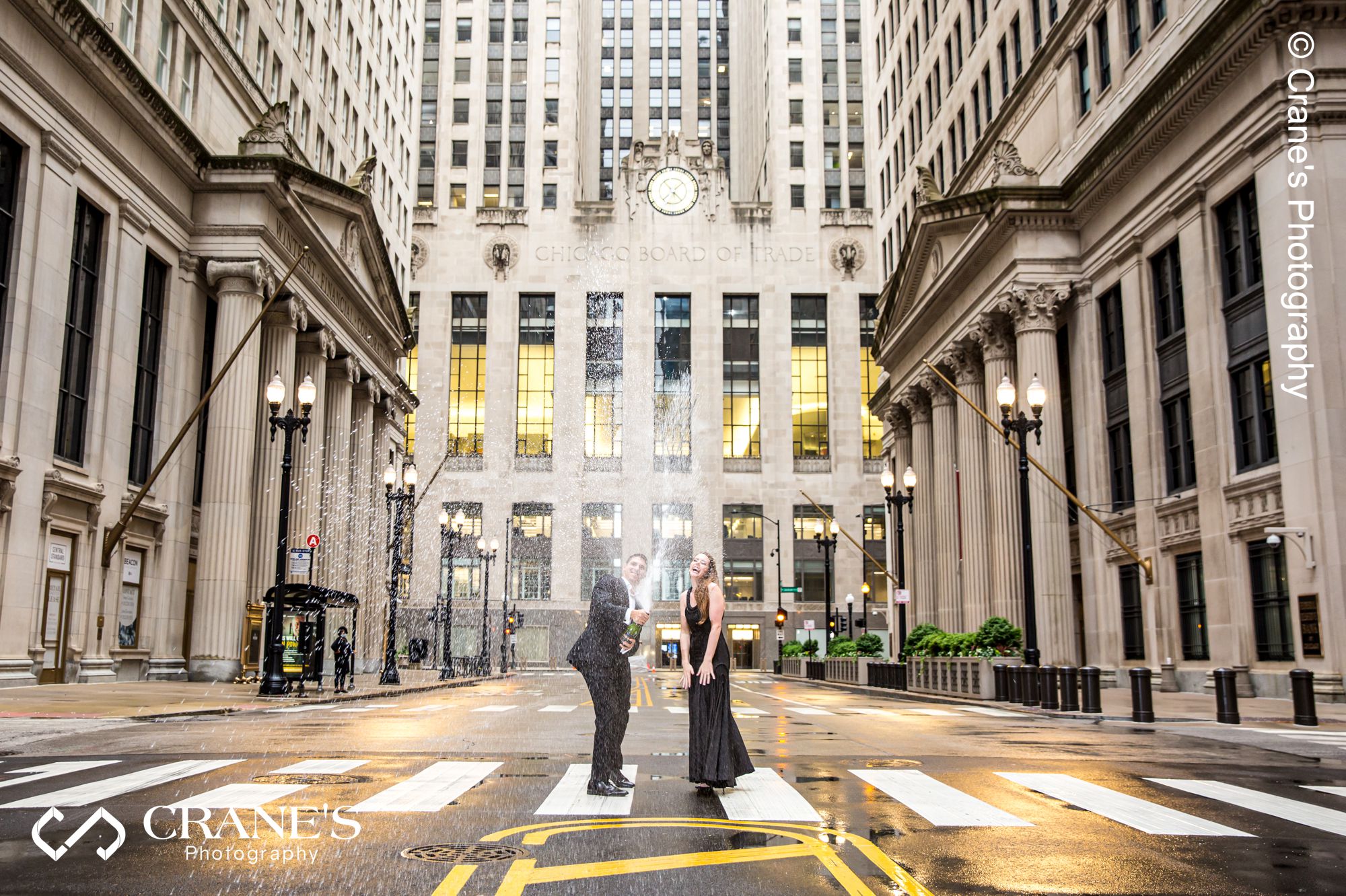 A modern couple pop a champagne for their engagement photo outside The Rookery Building in Chicago.