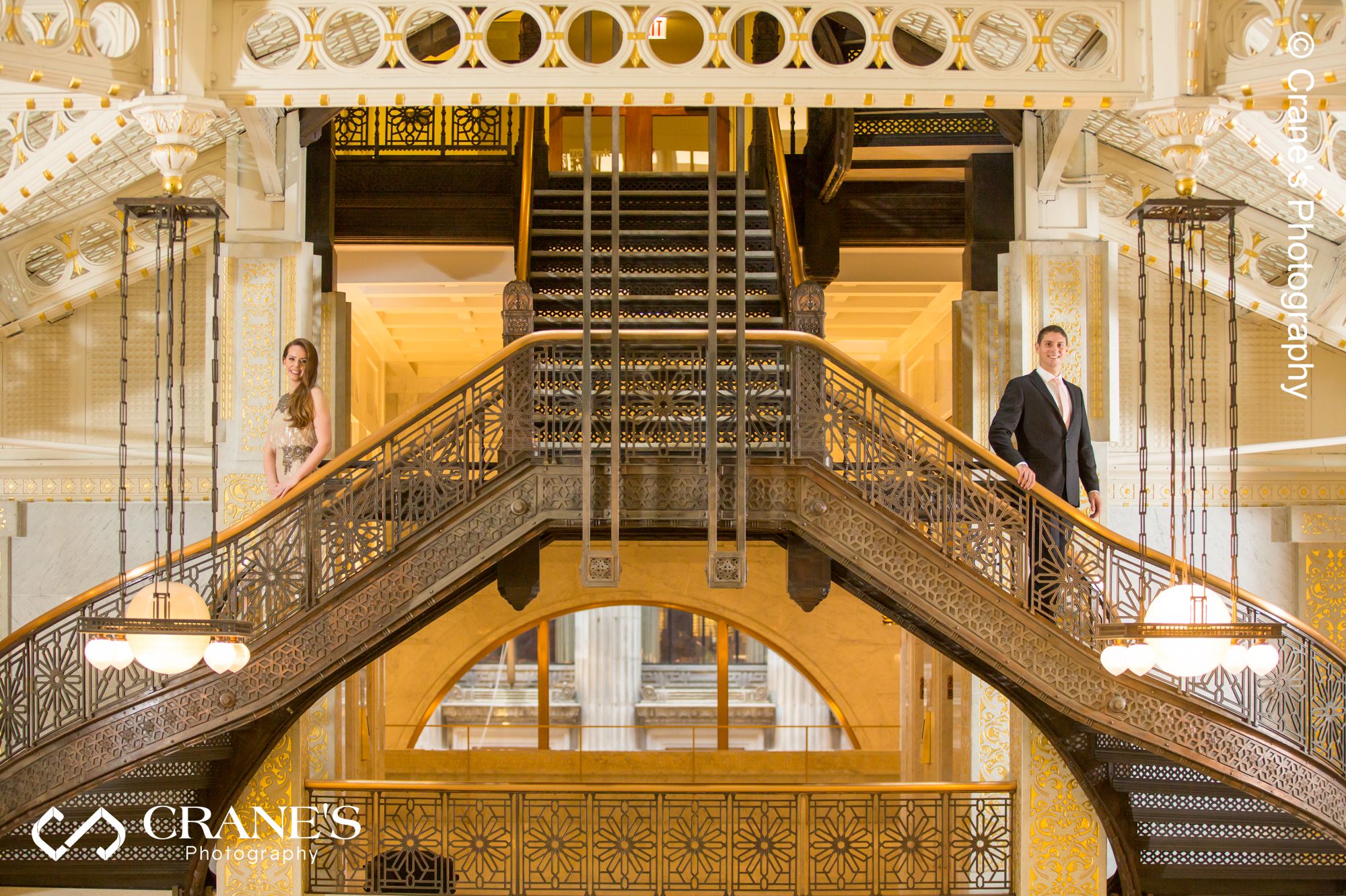 Stunning engagement photo of a couple standing on both sides of the spiral staircase at The Rookery in Chicago