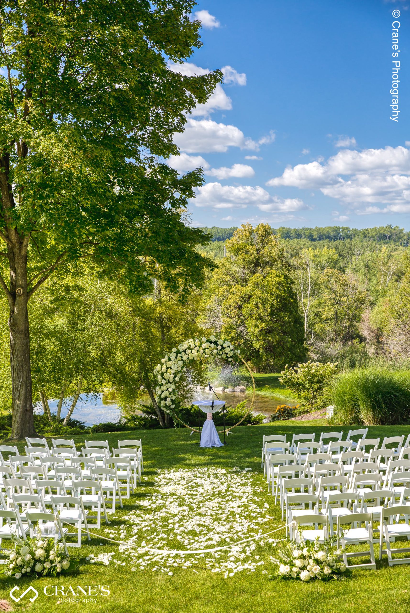 An outdoor wedding ceremony site with gorgeous curricular flower arch overlooking the ponds of the Big Foot Country Club.