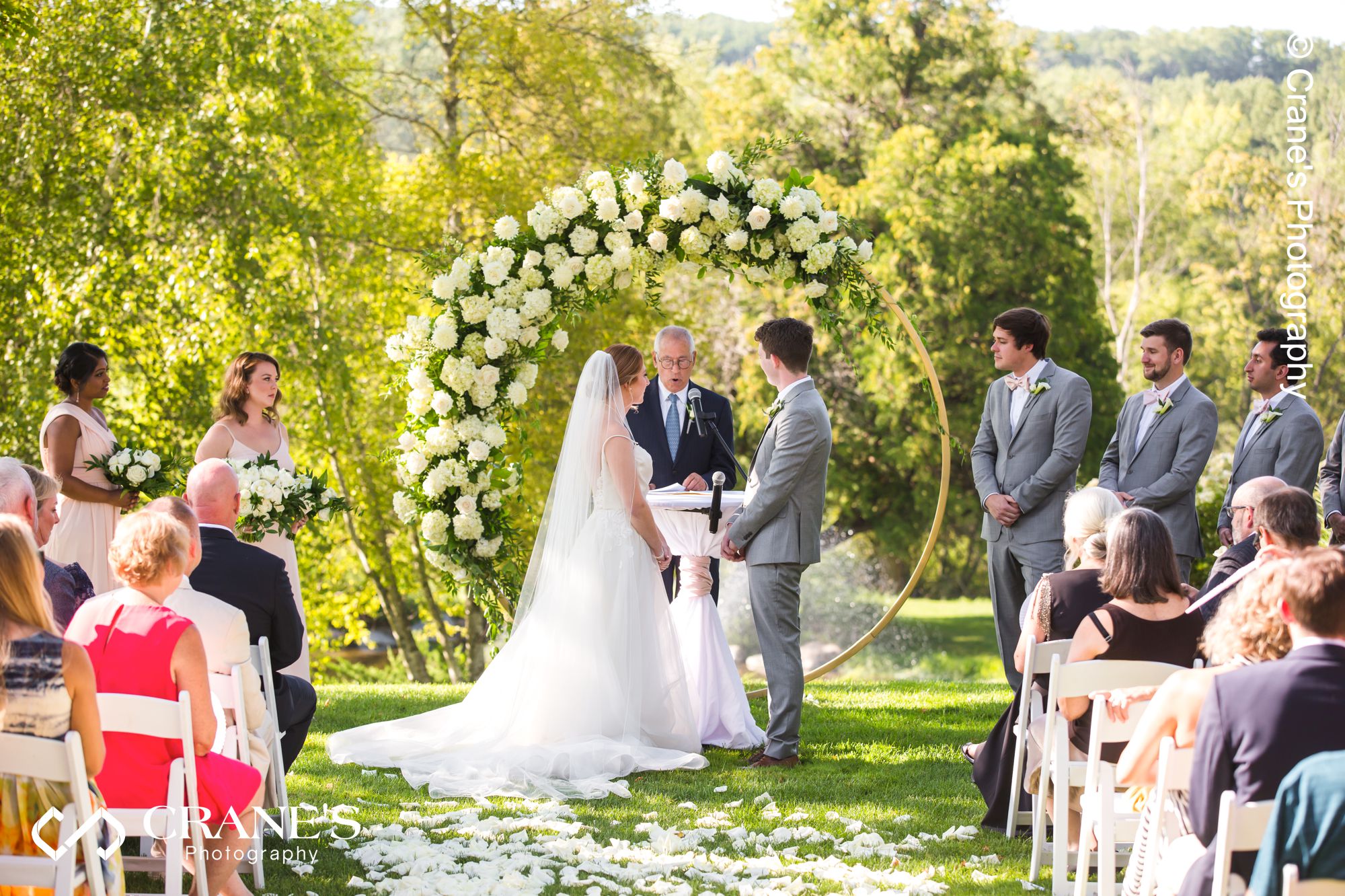 An outdoor wedding ceremony with curricular flower arch at Big Foot Country Club at Lake Geneva