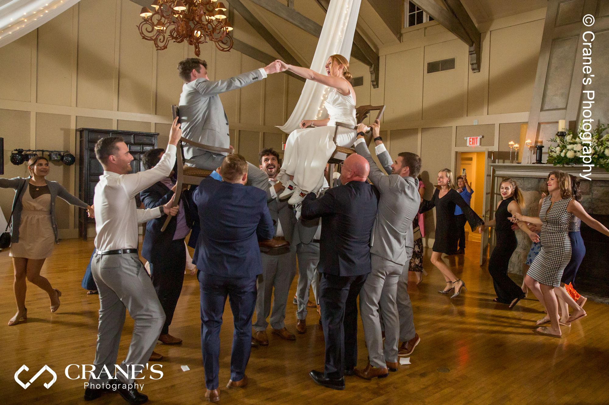 Jewish newlyweds are lifted into the air while their family and friends dance around them at a Big Foot Country Club