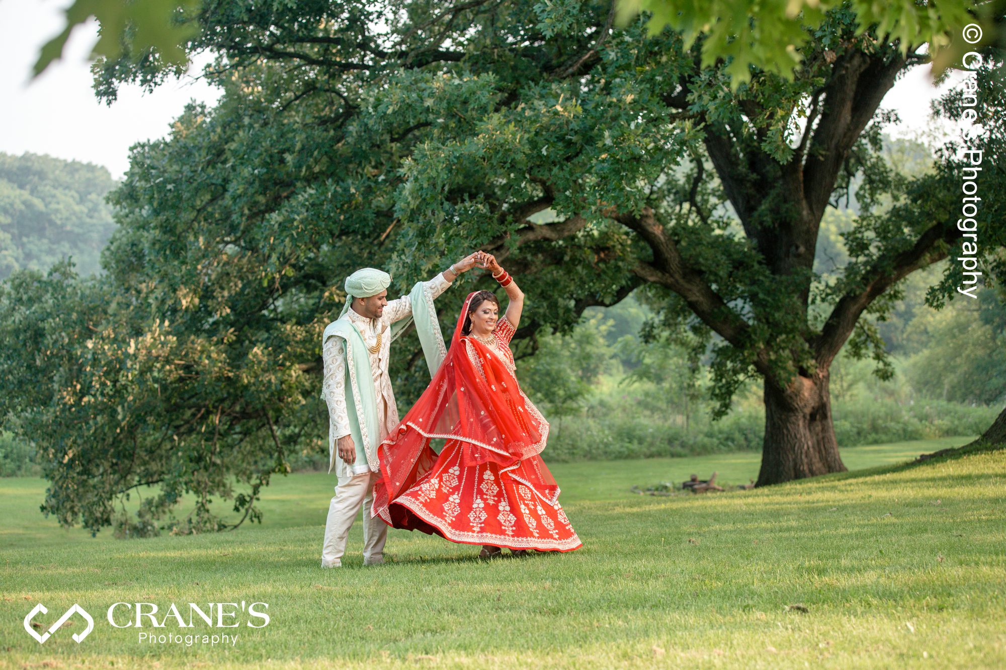 A groom is twirling his bride at Creek Bend Nature Center before their outdoor ceremony