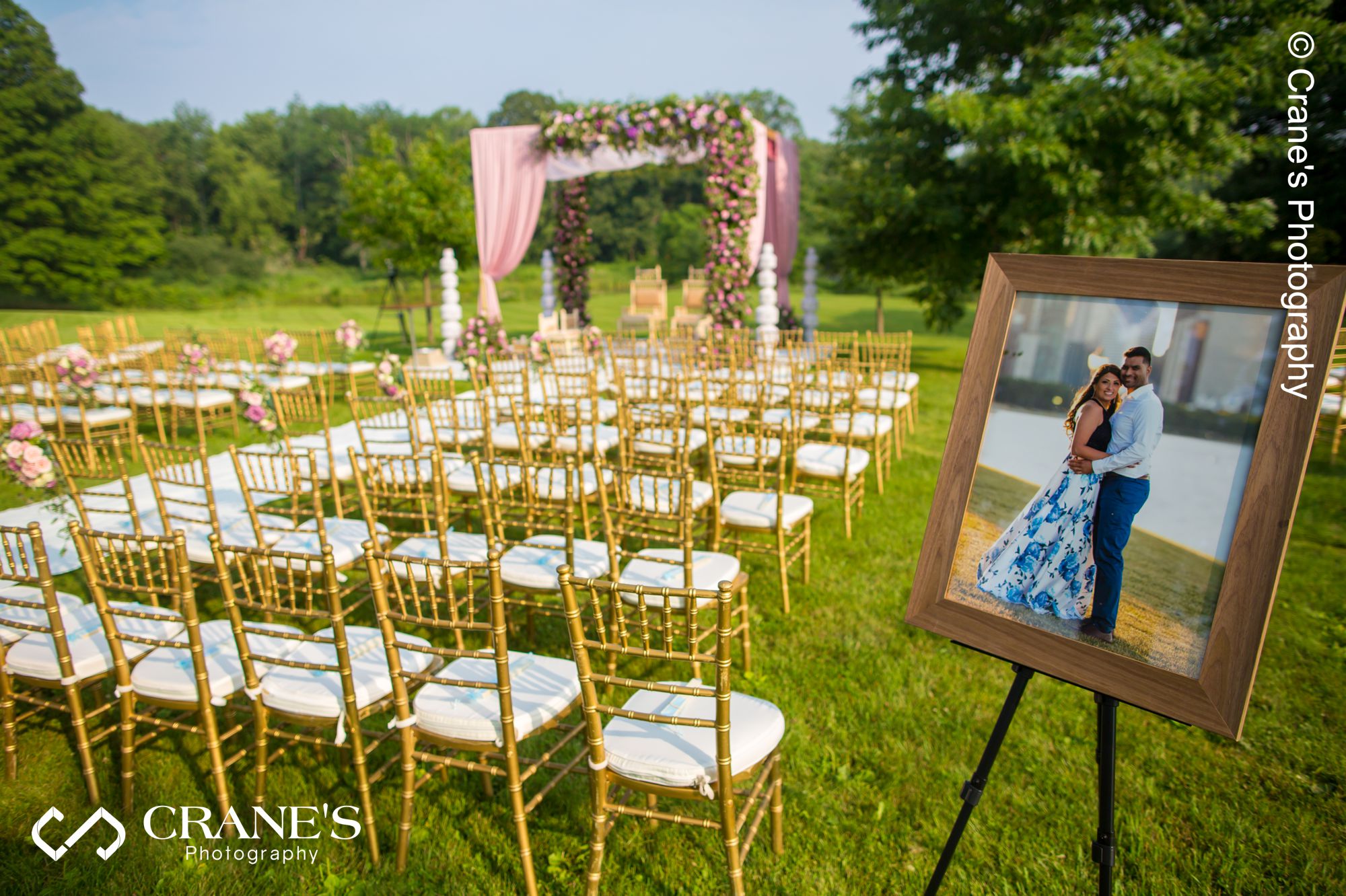 A printed engagement session photos displayed at an outdoor Indian wedding ceremony site.