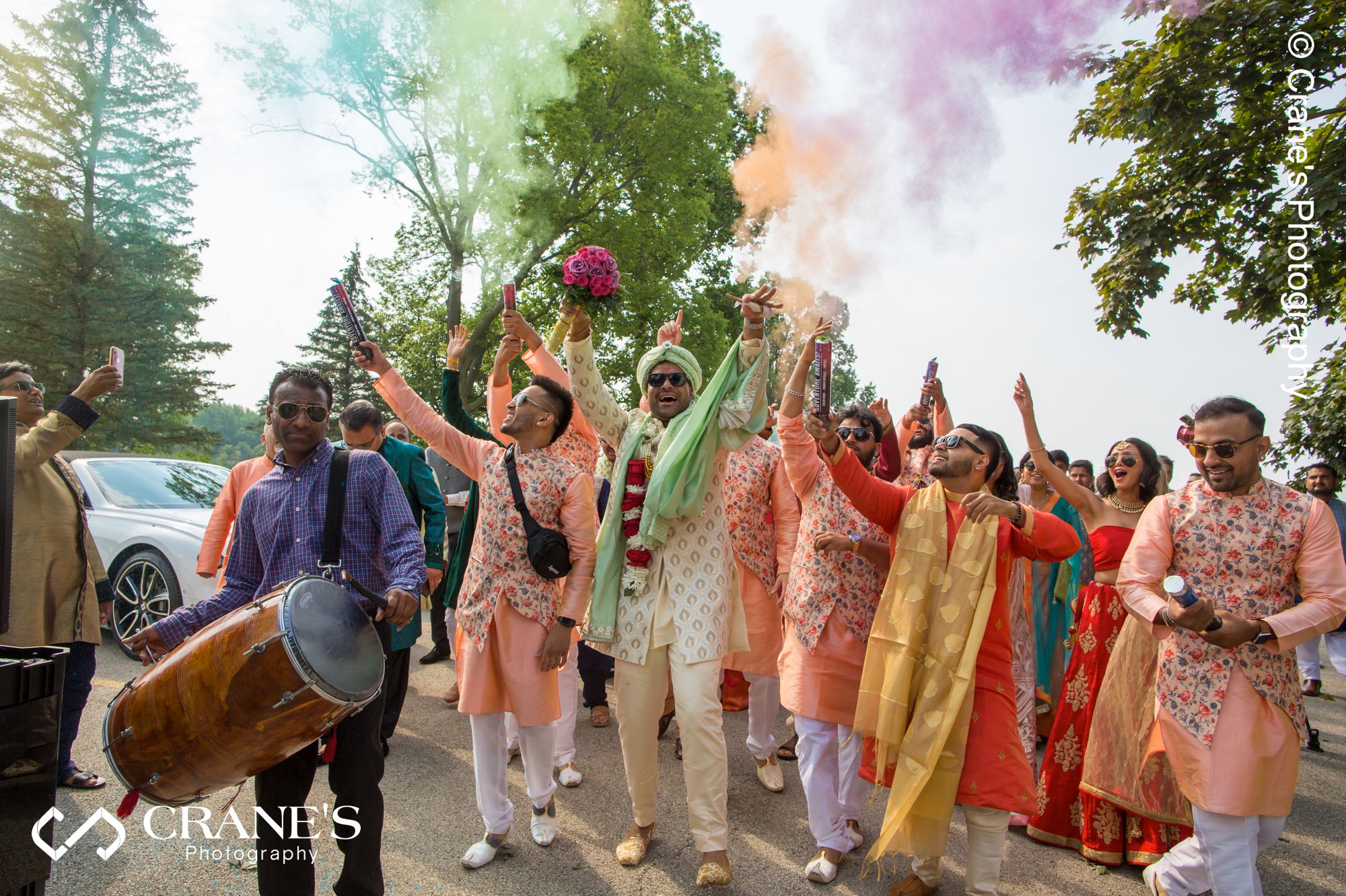 Indian groomsmen fire smoke bombs during a baraat before an outdoor wedding in Chicago
