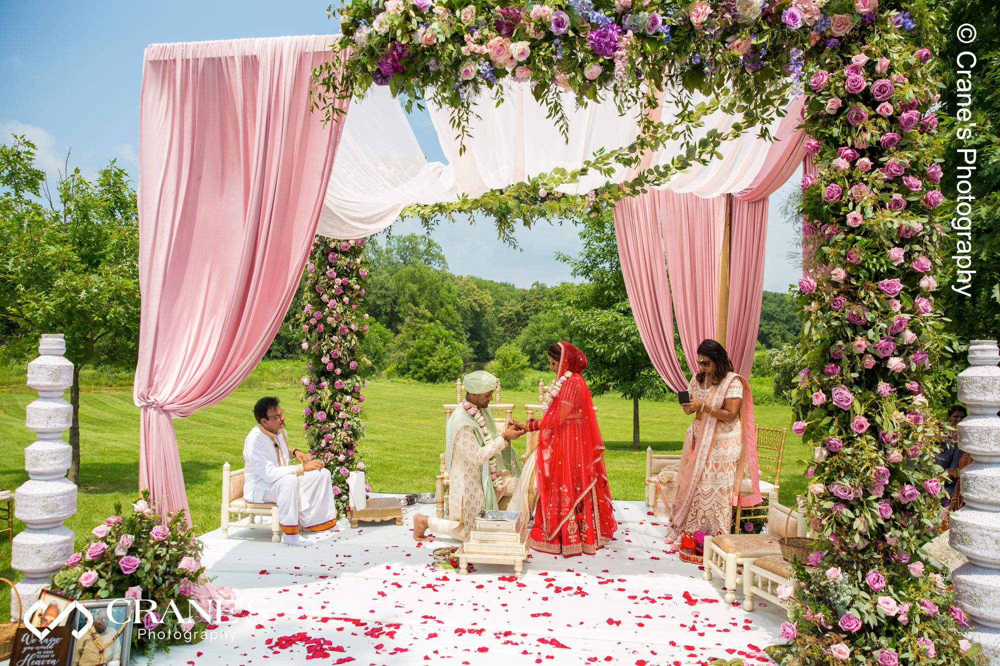 An Indian bride and groom exchange wedding ring under a mandap at an outdoor wedding ceremony site in Chicago