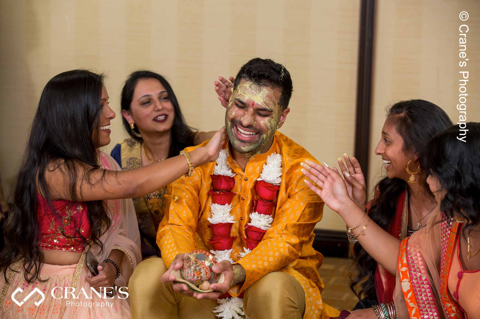 Applying the paste to the groom’s face during Haldi pre-wedding Indian ceremony