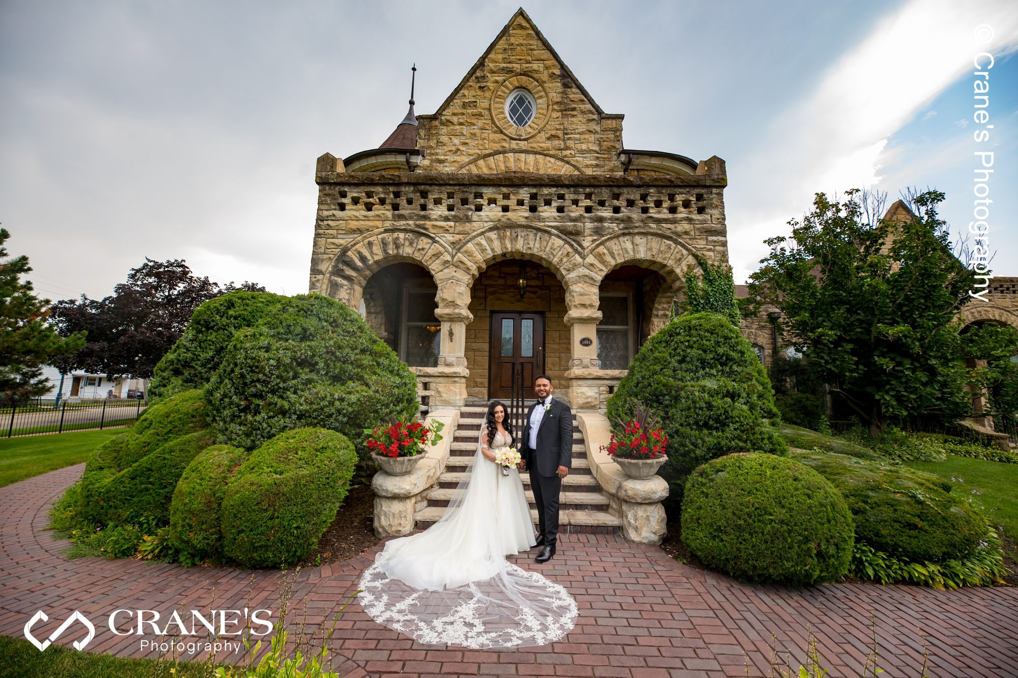 Wide angle wedding portrait of a bride and groom standing at the stairs of Haley Mansion