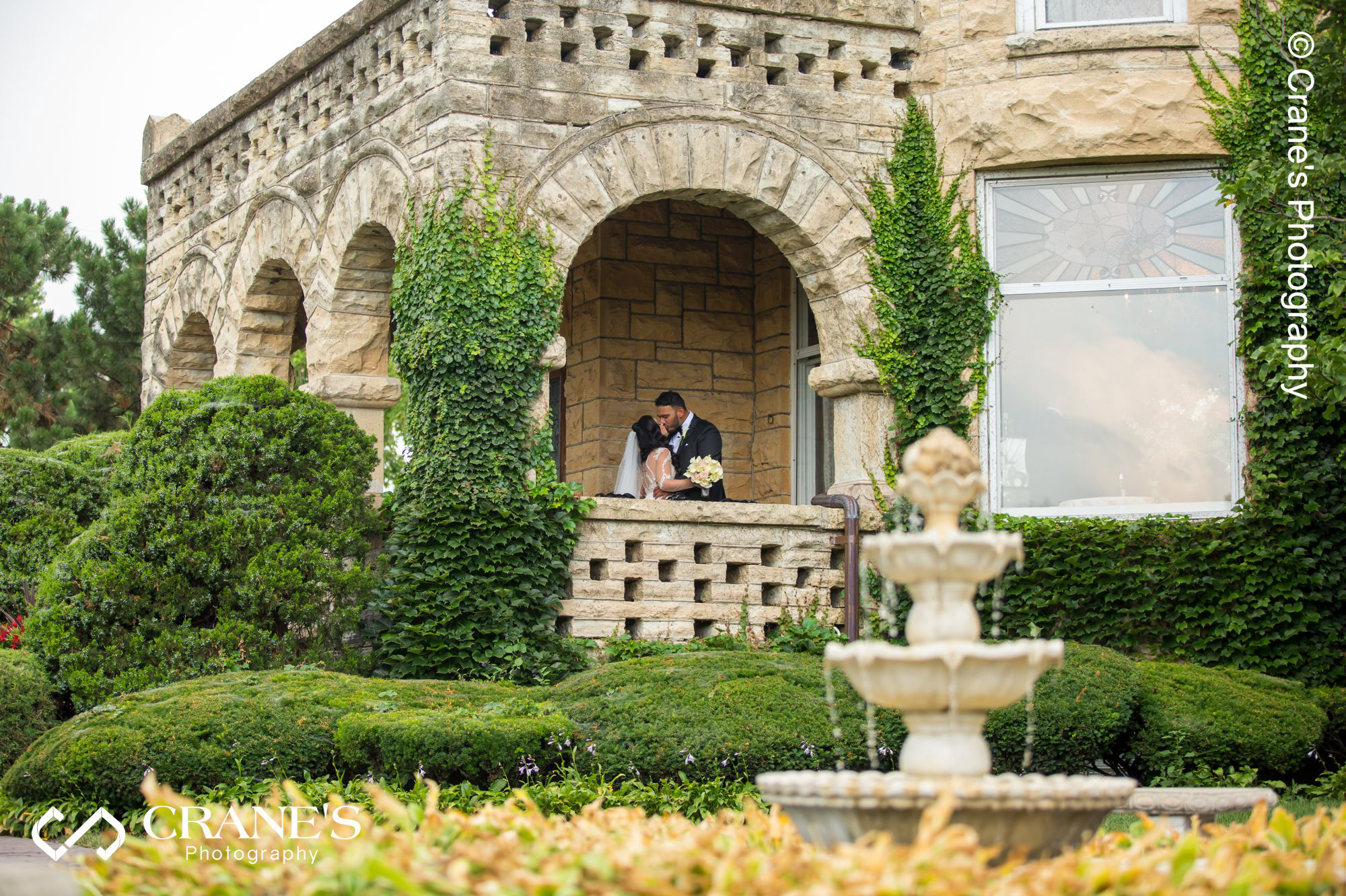 Bride and groom kissing under the front porch arch at Haley Mansion