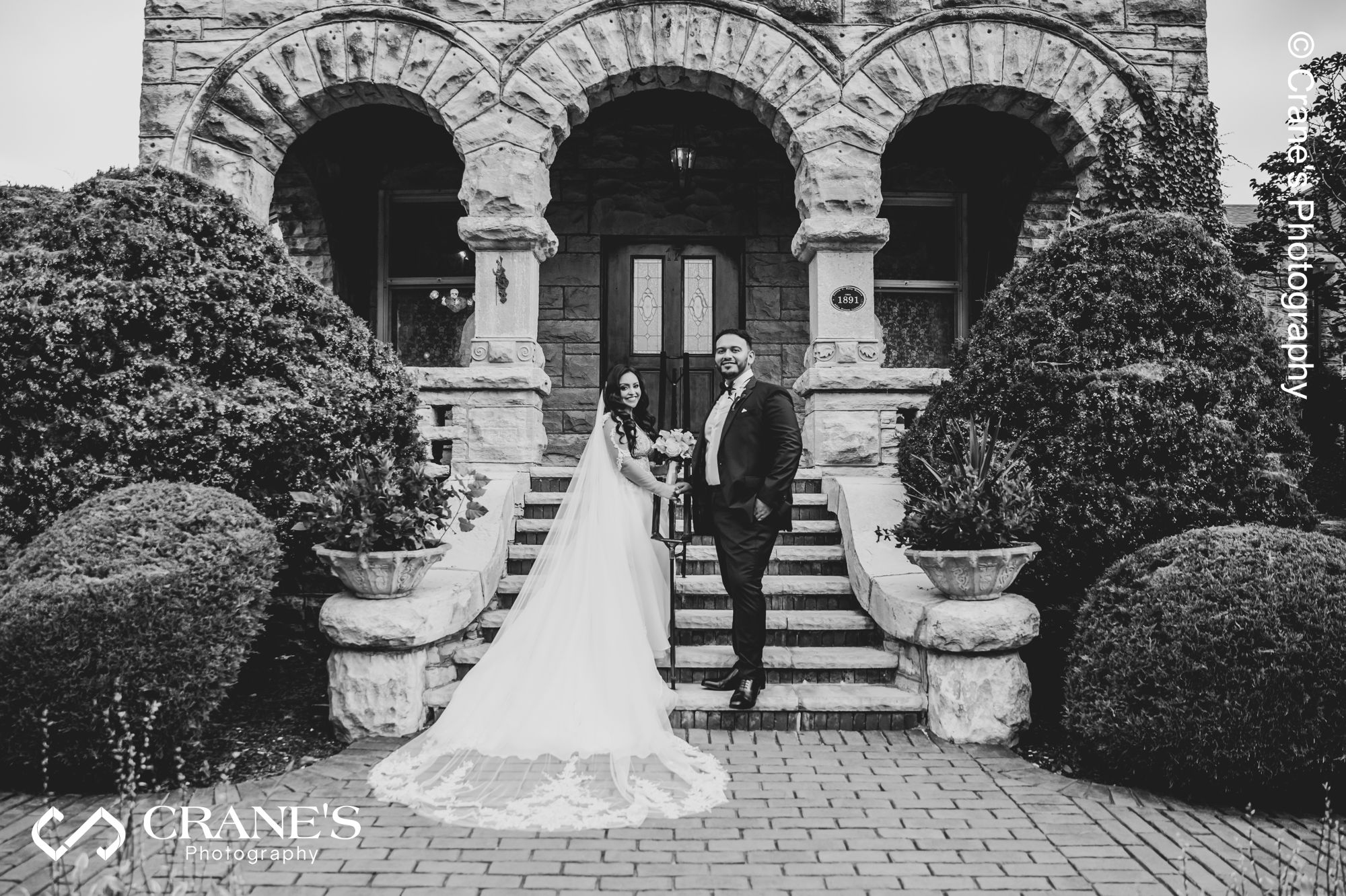 Bride wearing a long veil pose for a wedding photo at Haley Mansion