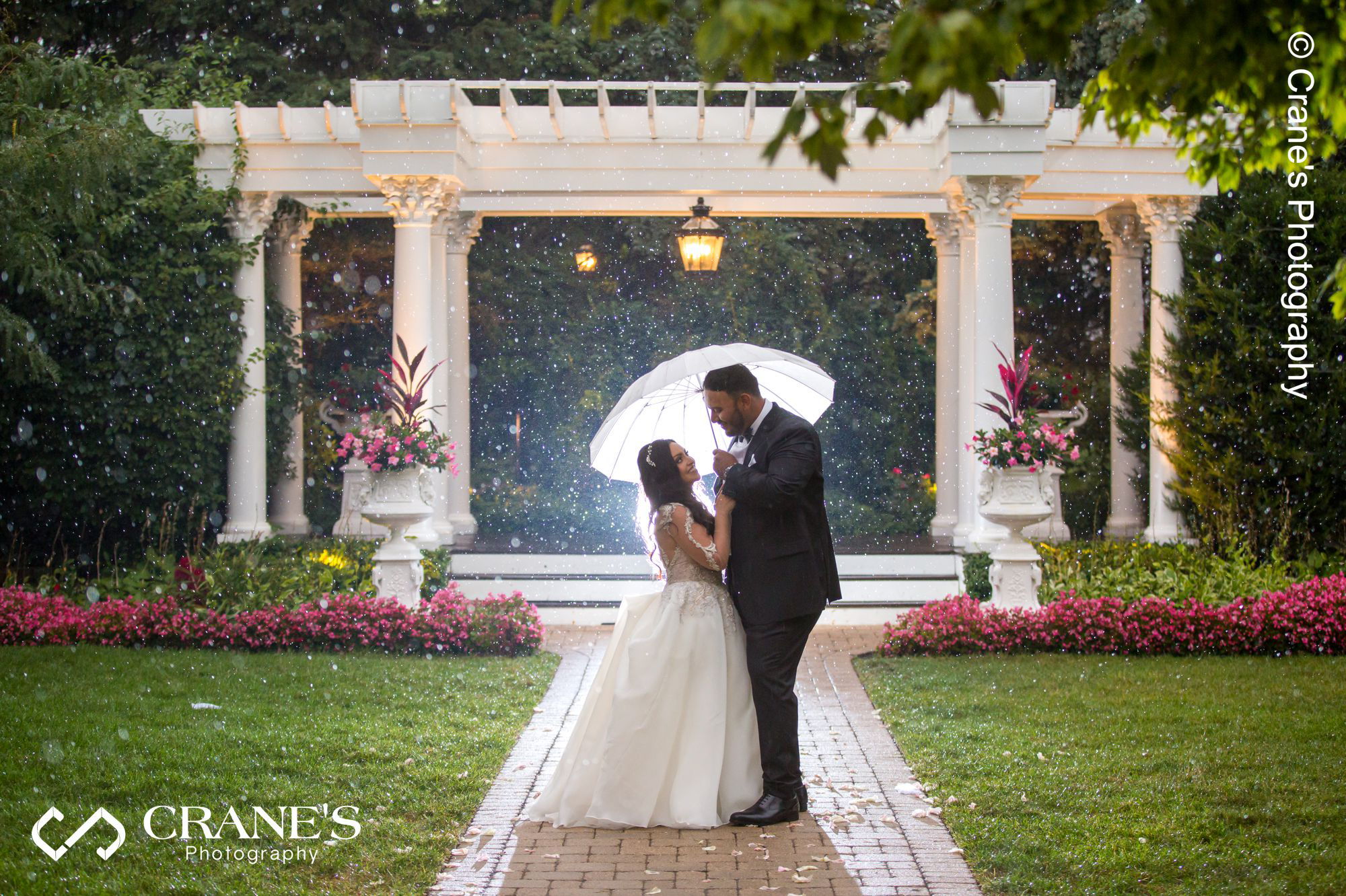 Bride and groom hold umbrella on a rainy wedding day at Haley Mansion