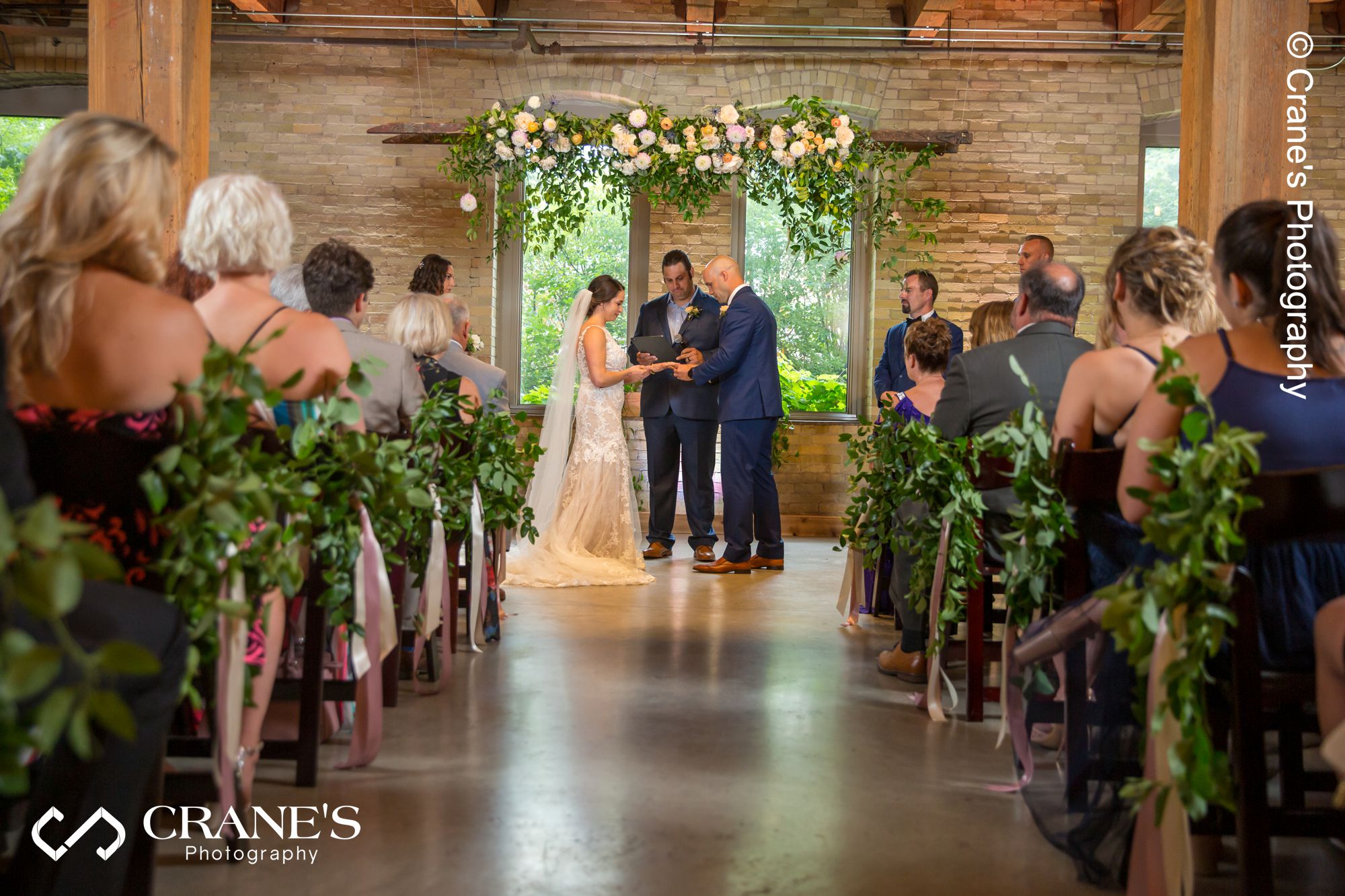 Bride and groom exchange rings during their indoor wedding ceremony at the Filament in Milwaukee