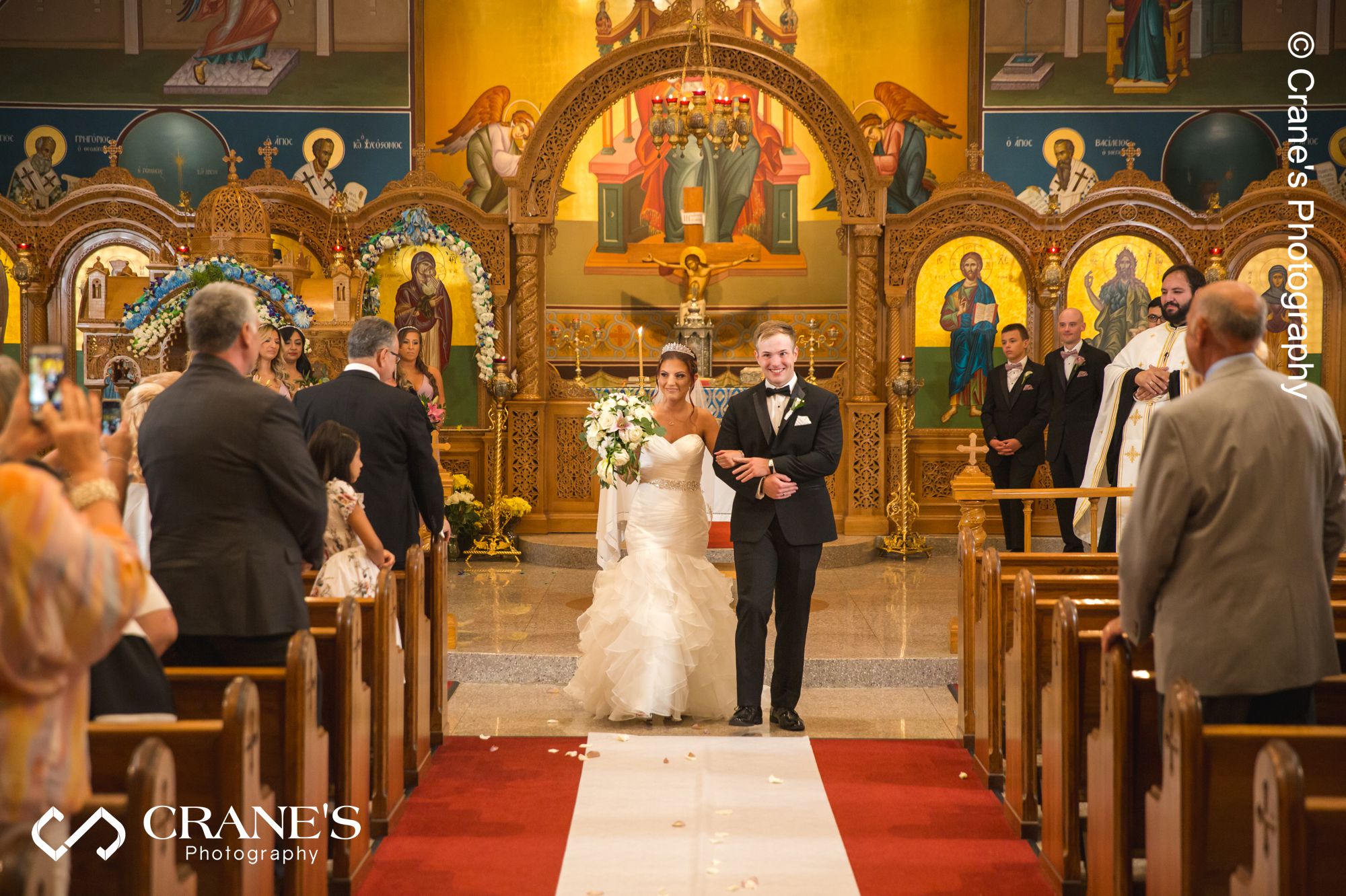 Bride and groom exit an orthodox wedding ceremony at St. Nectarios