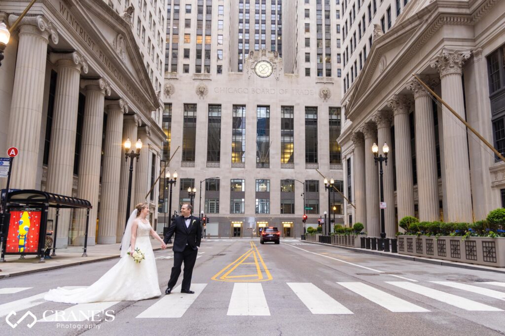 Bride and groom crossing the street in front of Chicago Board of Trade Building