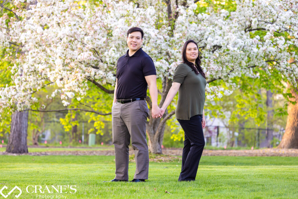 A couple is posing for a spring engagement photo with a flowering free in the background at Cantigny Park in Wheaton, IL.