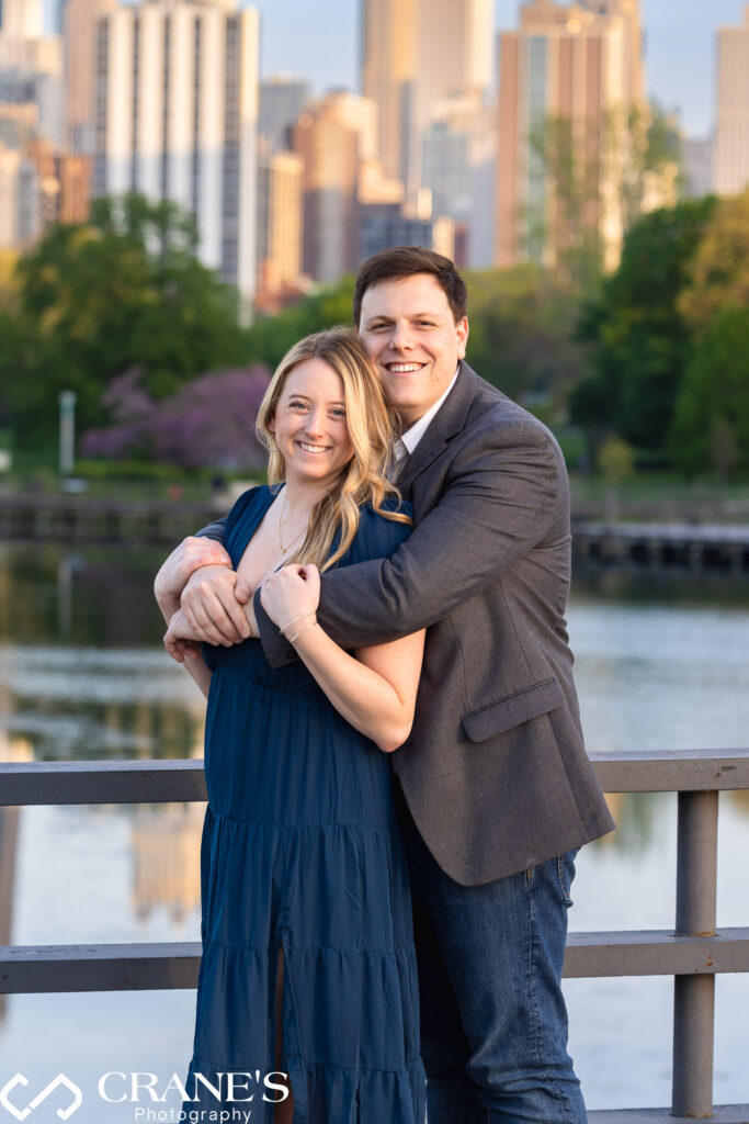 An engaged couple are posing for a photo near the South Pond at Lincoln Park