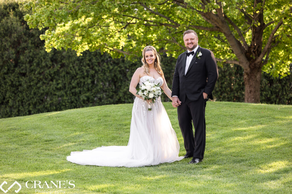 A bride with an elegant wedding dress and a groom with black suit post on the greens at Royal Melbourne Country Club.