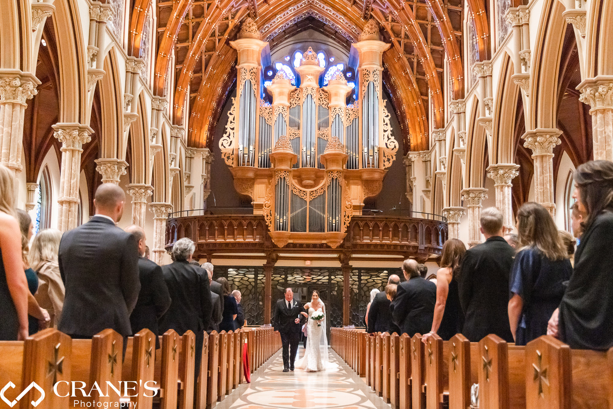 A bride and her dad are walking down the aisle on a wedding day at Holy Name Cathedral.