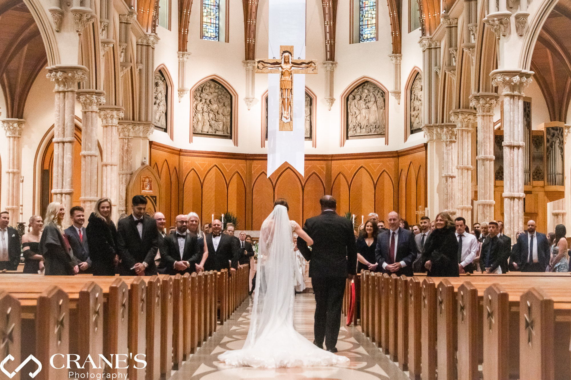 A view from behind of a bride and her dad walking down the aisle at Holy Name Cathedral.