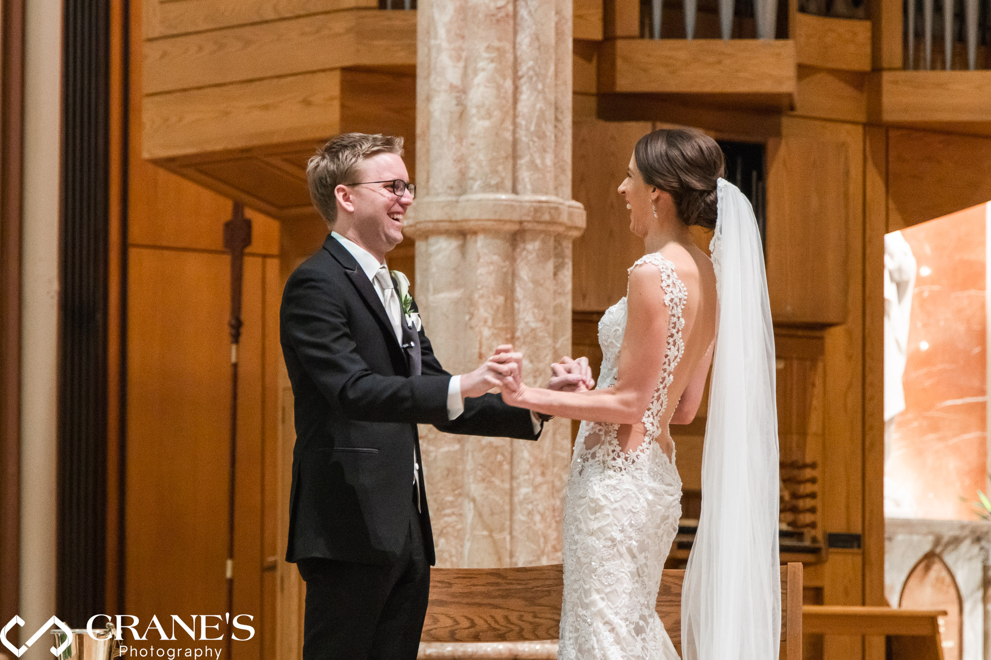 Newlyweds holding hands a laughing during their wedding ceremony at Holy Name Cathedral in Chicago.