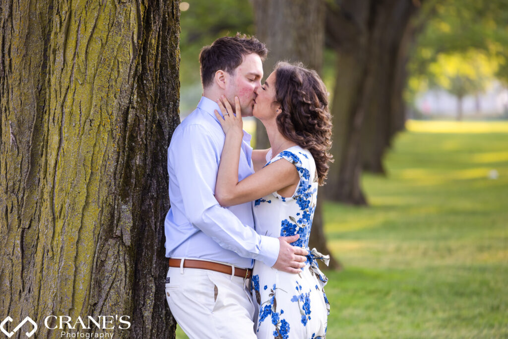 An engaged couple kissing at Cantigny in the summertime.