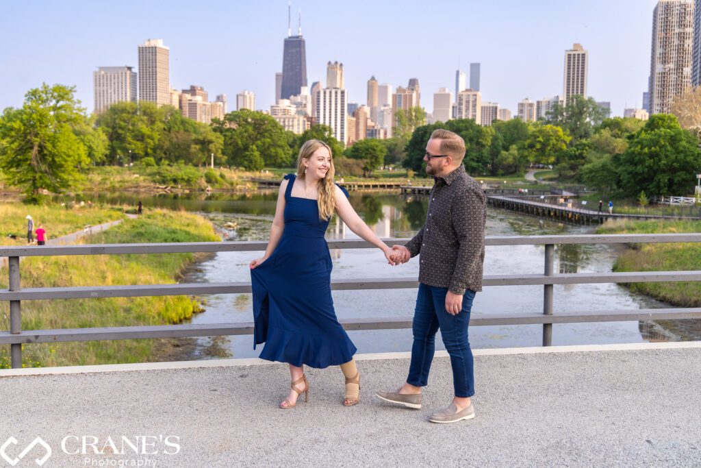 Engaged couple wearing blue cloths walking on the bridge over the South Pond in Lincoln Park.