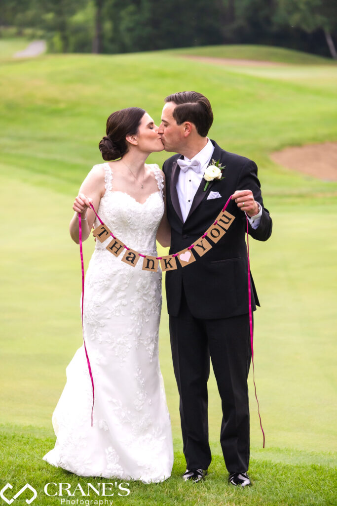 Bride and groom holding a "Thank You" sign near the 18th green at Royal Melbourne.