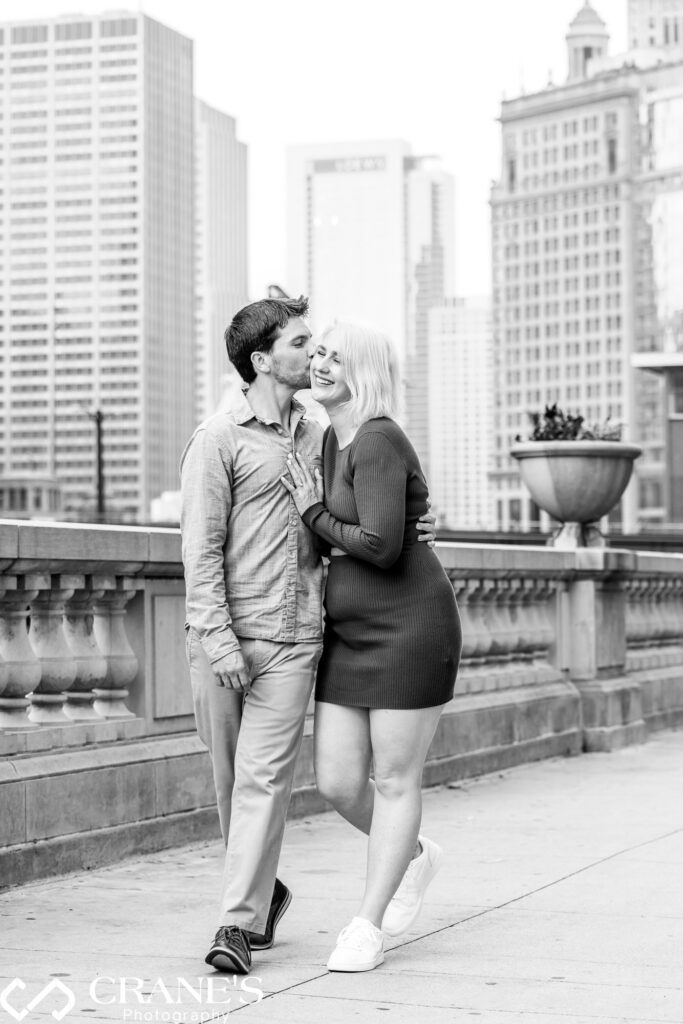 Black and white image of guy kissing her fiancée at the Chicago Riverwalk.