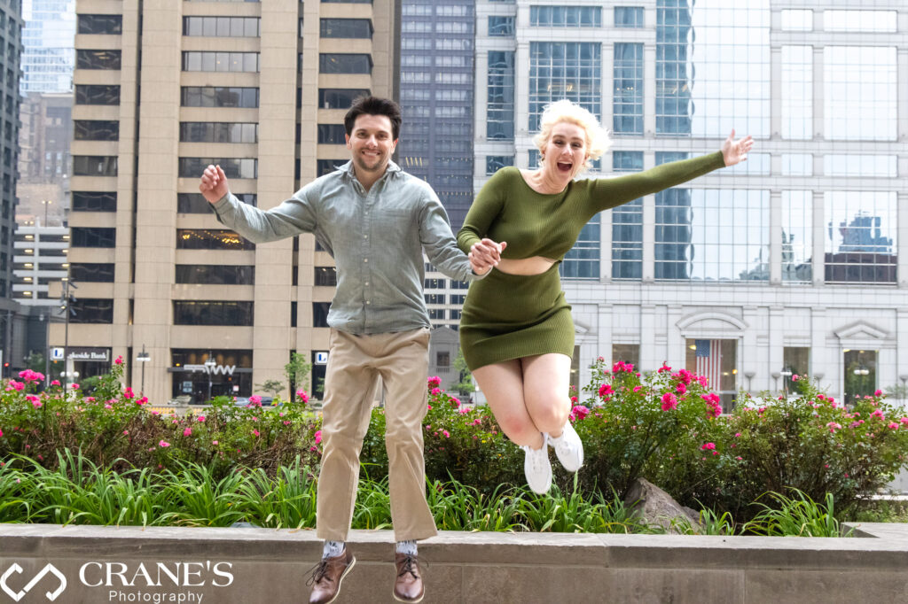 A fun engagement photo of a couple jumping in the air next to the Riverwalk in Chicago.