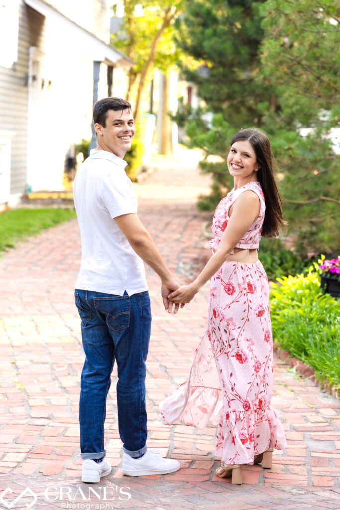 An engaged couple pose for a photo on a cobblestone street in downtown Long Grove.