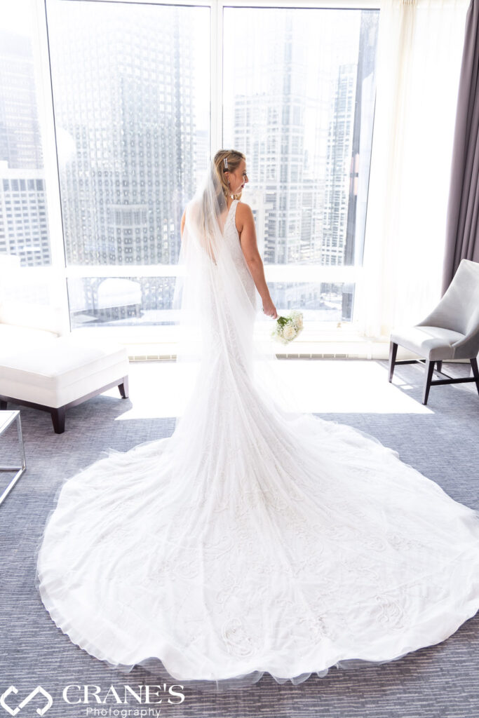 A bride wearing a white wedding dress with a long train at a suite at Trump Chicago
