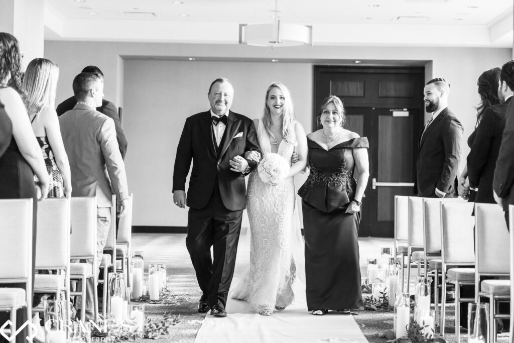 Lisabeth is walking down the aisle with her parents at her wedding ceremony at Trump Tower