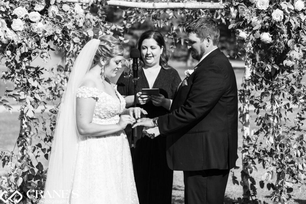 Bride and groom exchange rings at an outdoor wedding ceremony at Bloomingdale Golf Club.