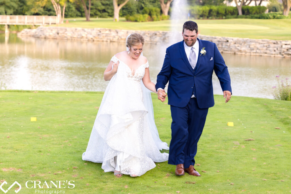 Bride and groom walking hand-in-hand on the greens at Bloomingdale Golf Club with the fountain in the background.