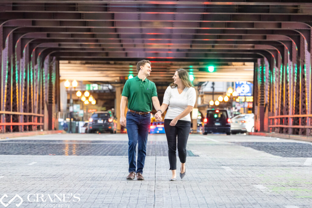An engaged couple is walking under the "L" track at Well Street bridge.