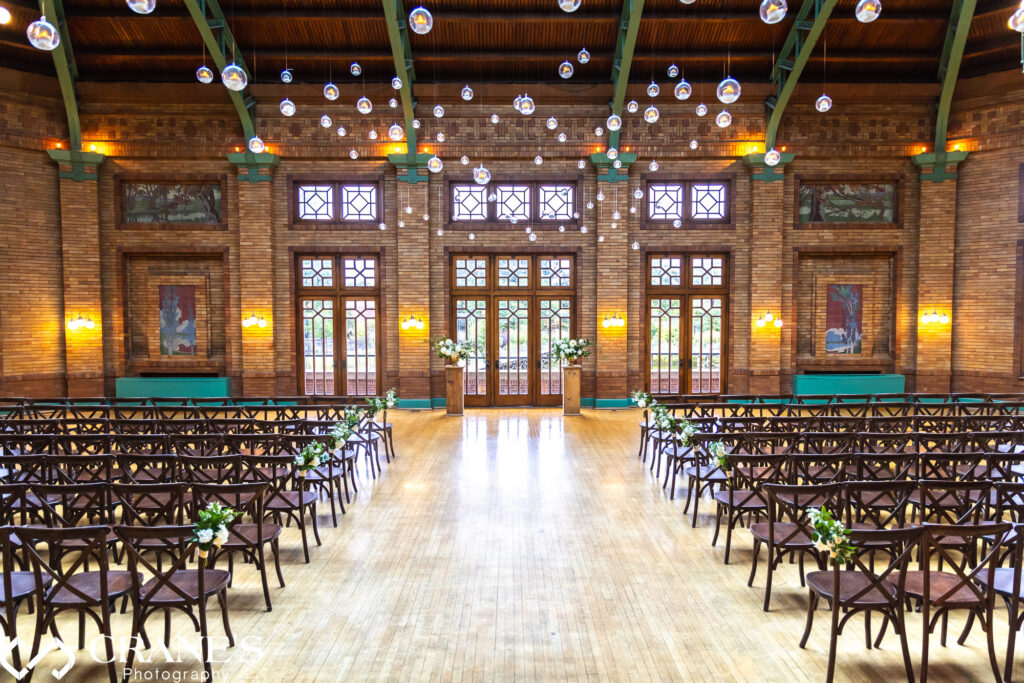 Wedding ceremony setting at the Great Hall in Cafe Brauer featuring rustic chairs and suspended floating candles from the ceiling.