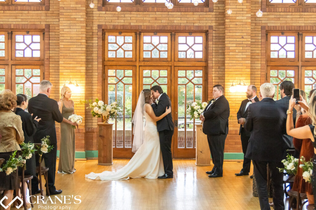 The bride and groom share their first kiss as a married couple in the Great Hall at Cafe Brauer.