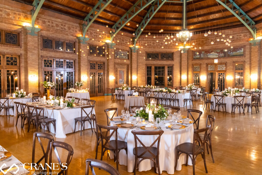 Wedding reception at Cafe Brauer adorned with candles, abundant flowers, lush greenery, and suspended floating candles from the ceiling.
