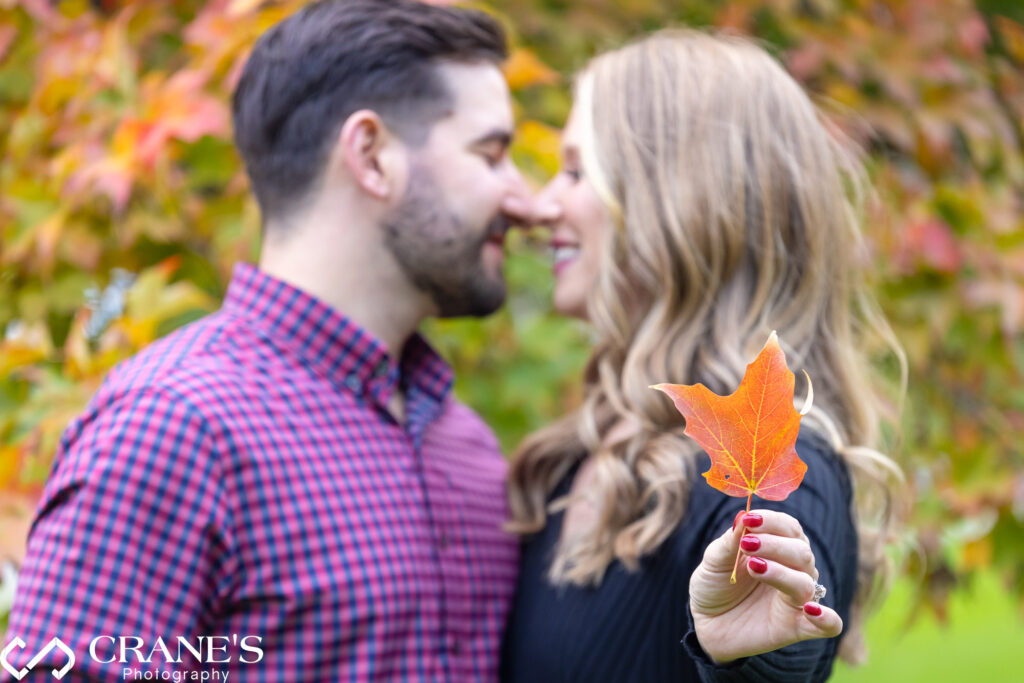 A fall engagement session at Cantigny Park featuring Jenna, who is holding a vibrant red leaf.