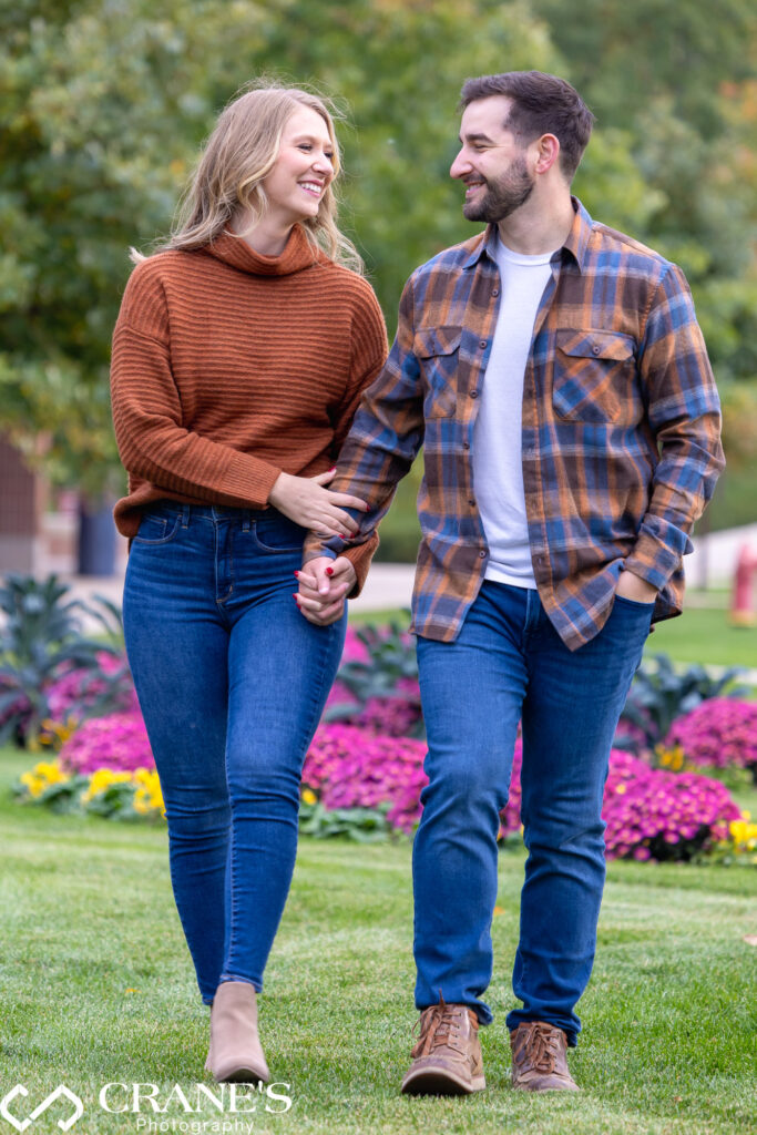 An engaged couple, dressed in casual blue jeans, strolling through the picturesque surroundings of Cantigny Park.